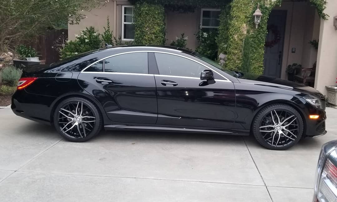 Black Mercedes sedan with tinted windows parked on a concrete driveway.