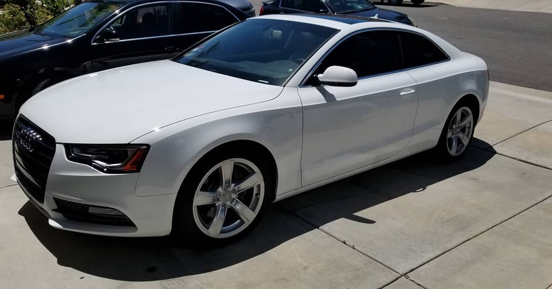 White Audi A5 coupe parked on a driveway with tinted windows and a sunroof.