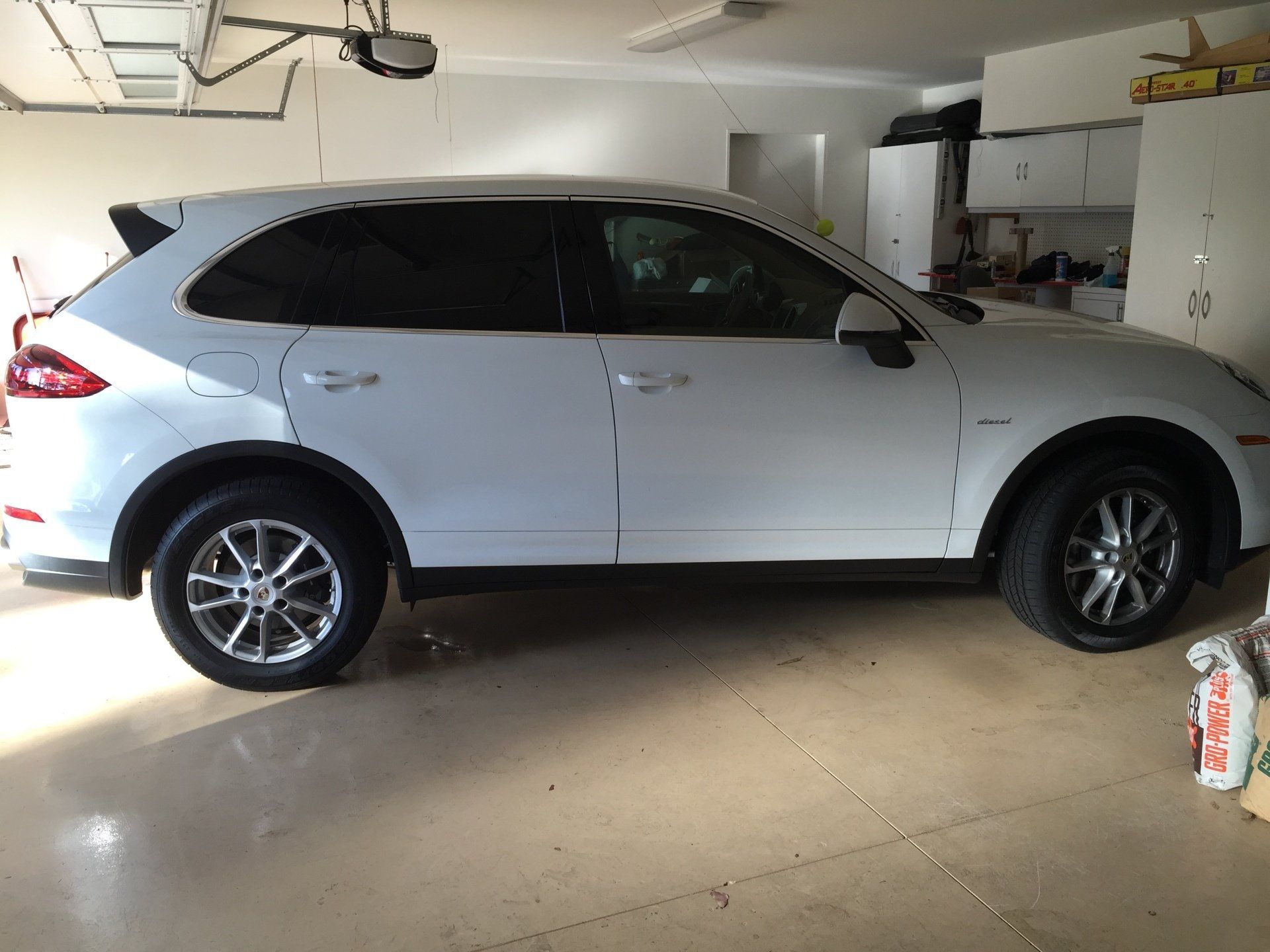 White Porsche SUV parked in a garage with a concrete floor.