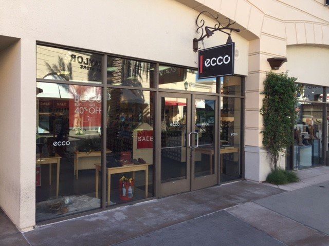 Ecco shoe store storefront with large windows, sign, and double doors.
