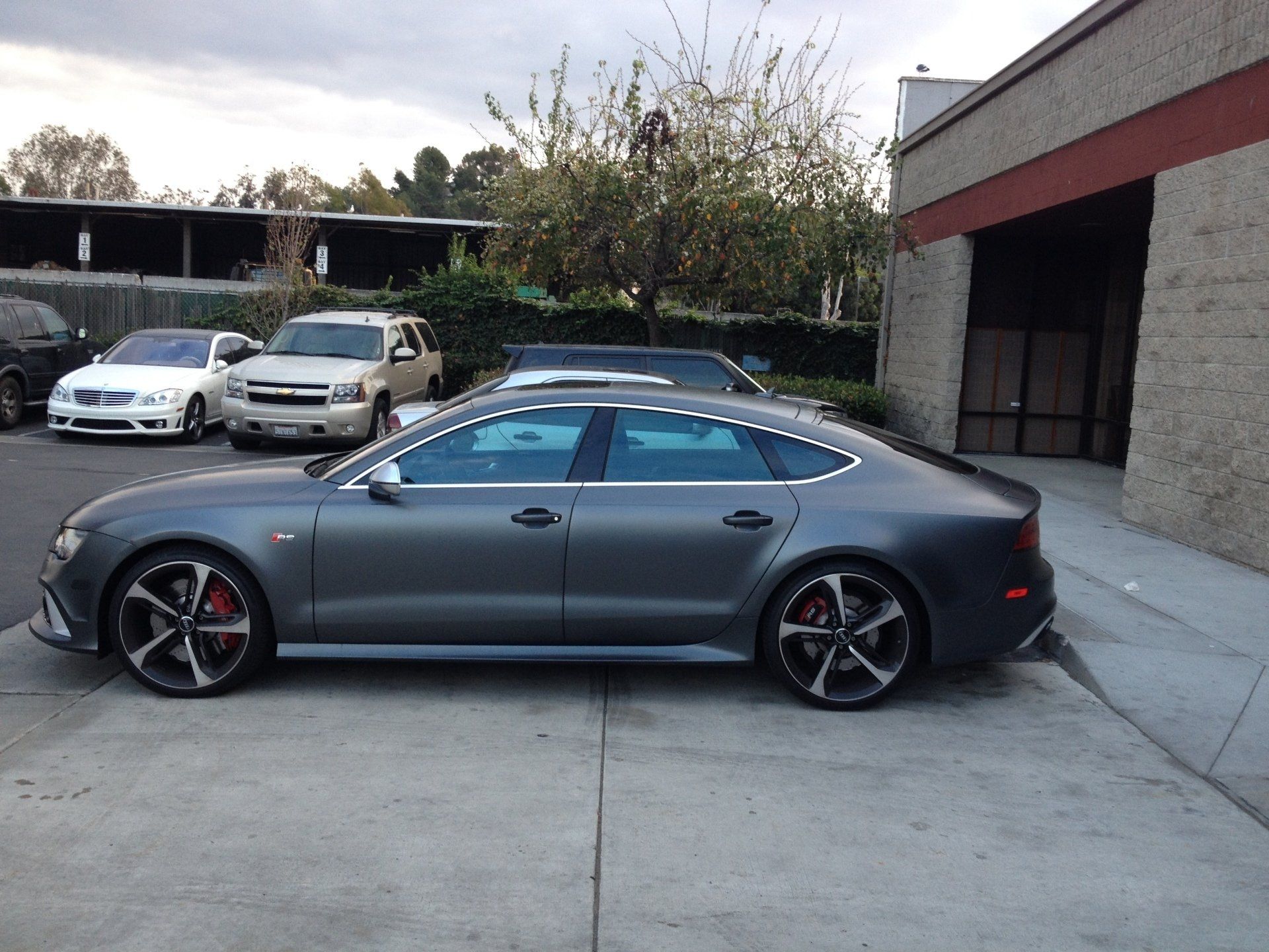 Gray Audi sedan parked outside, with red brake calipers. Other cars and building in the background.