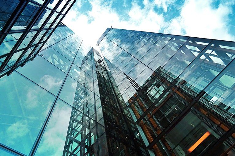 Skyscrapers with reflective glass facades against a cloudy blue sky.