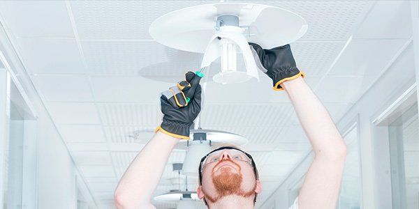 Electricians — Man Fixing Lamp in Albuquerque, NM Electricians — Man Fixing Lamp in Albuquerque, NM