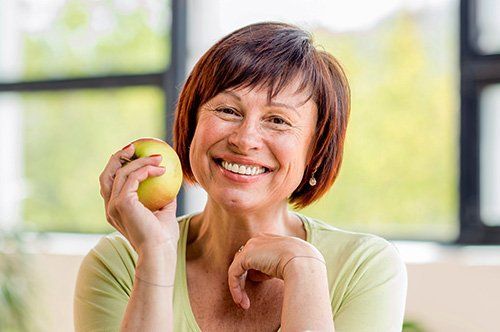 Dental Crowns Older woman holding apple