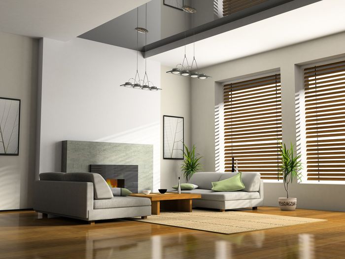 Timber blinds on windows of large open loungeroom, with grey couch in front of fireplace, coffee table, mat, and pendant lights.