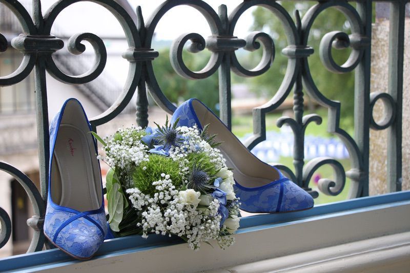 Een paar blauwe schoenen en een boeket bloemen op een vensterbank