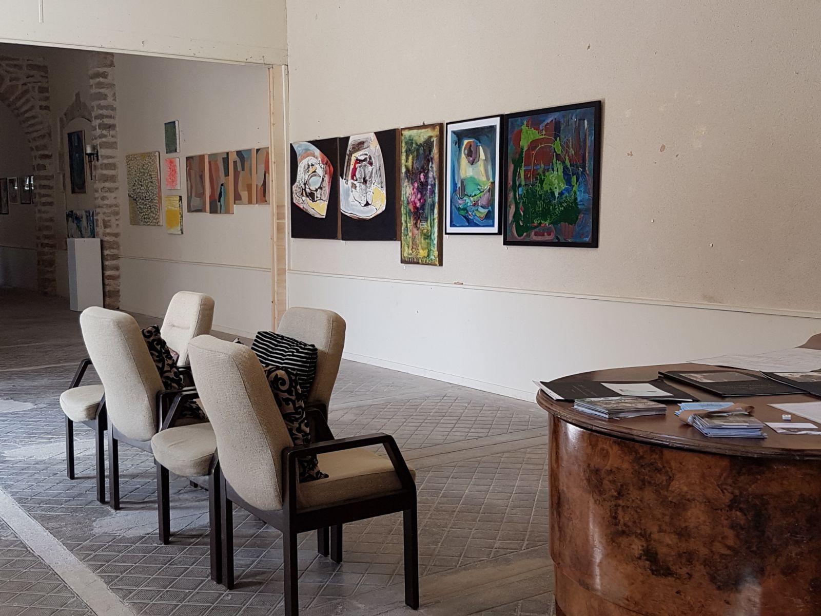 Een kamer met stoelen en schilderijen aan de muur