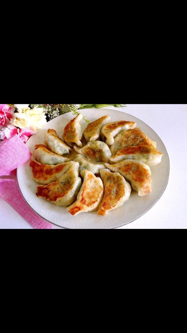 Een wit bord met gefrituurde dumplings op een tafel.