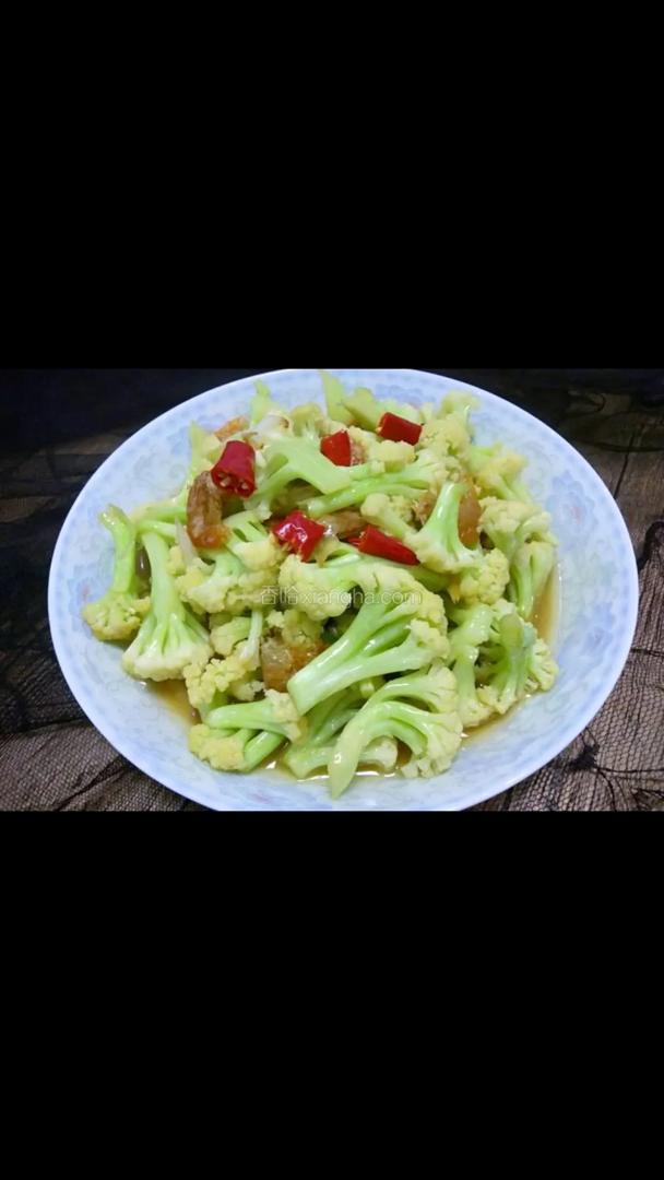 Een bord roergebakken bloemkool met rode paprika op tafel.