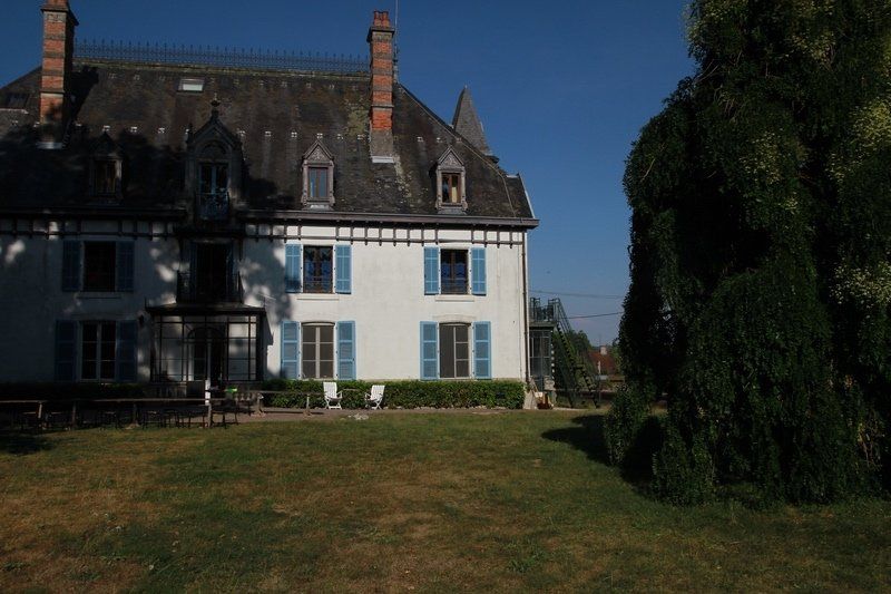 Een groot wit huis met blauwe luiken voor de ramen