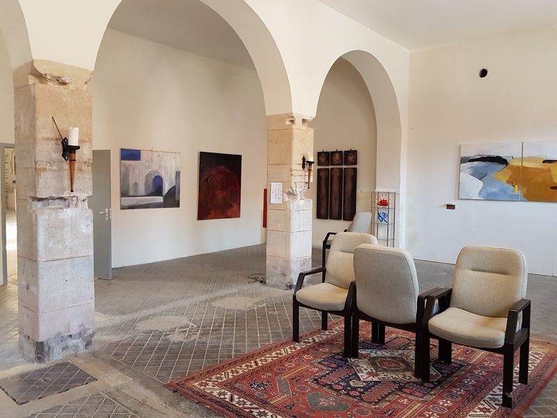Een kamer met stoelen en schilderijen aan de muur