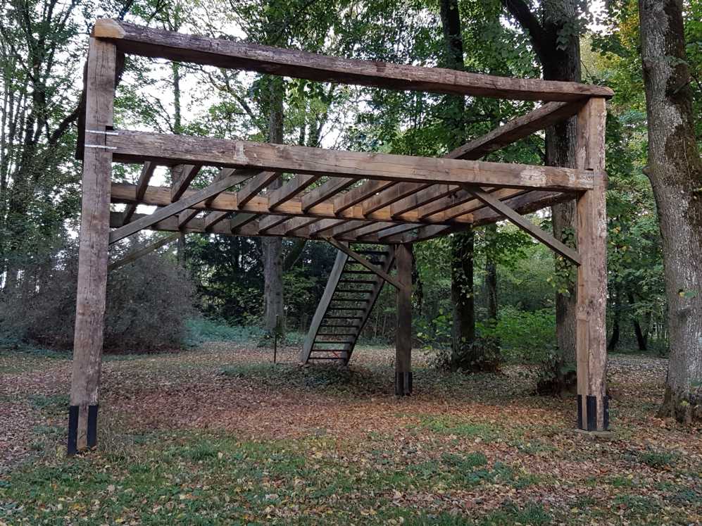 Een houten constructie met trappen midden in een bos.
