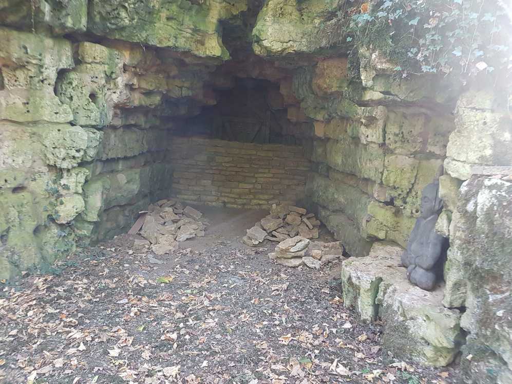 Een grot vol stenen en bladeren midden in een bos.