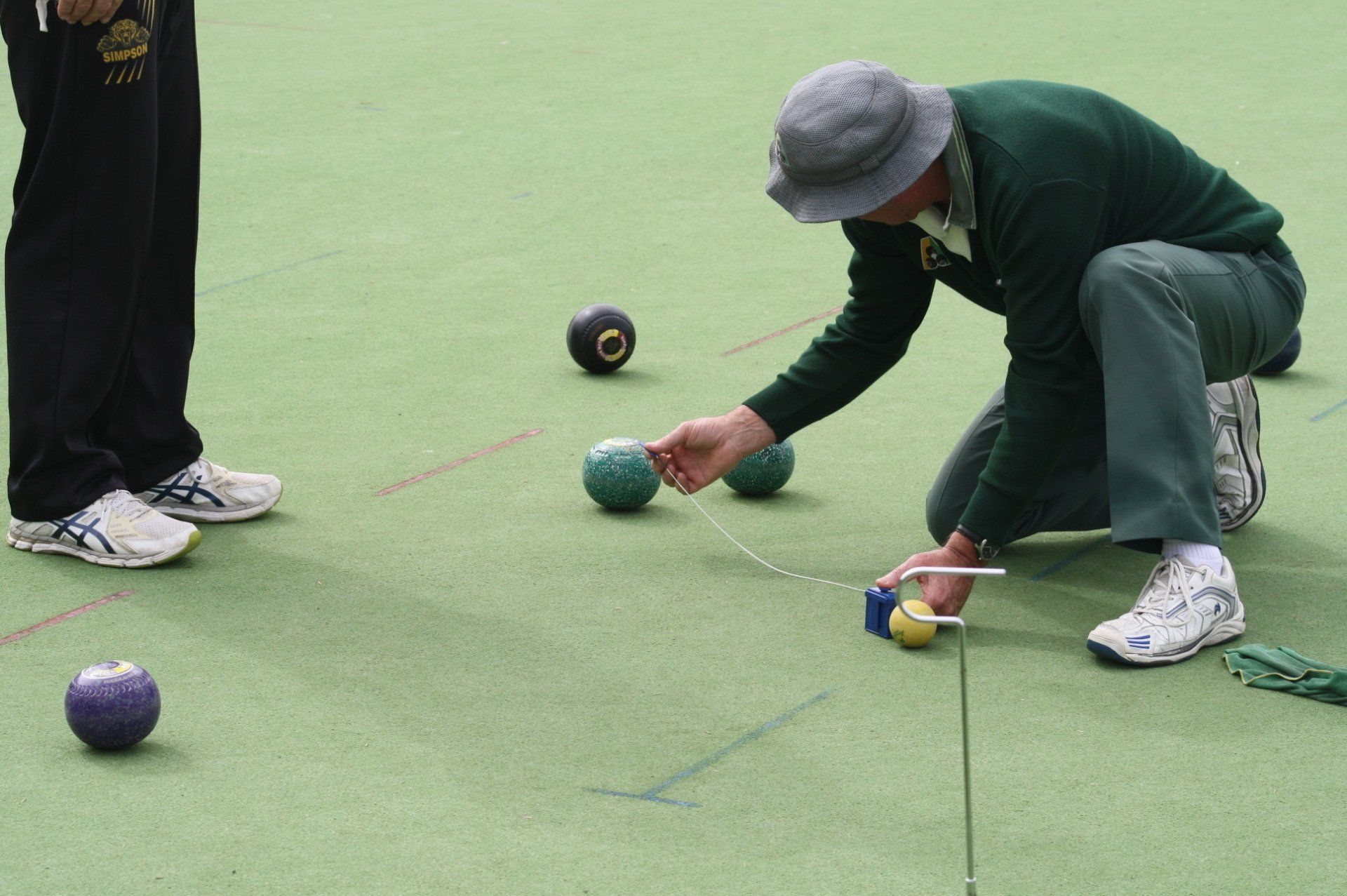Bowler measuring distances between bowls and the jack