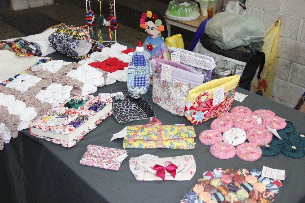 Mesa de artesanato: colchas, bolsas, bonecas e outros artigos feitos à mão à venda.