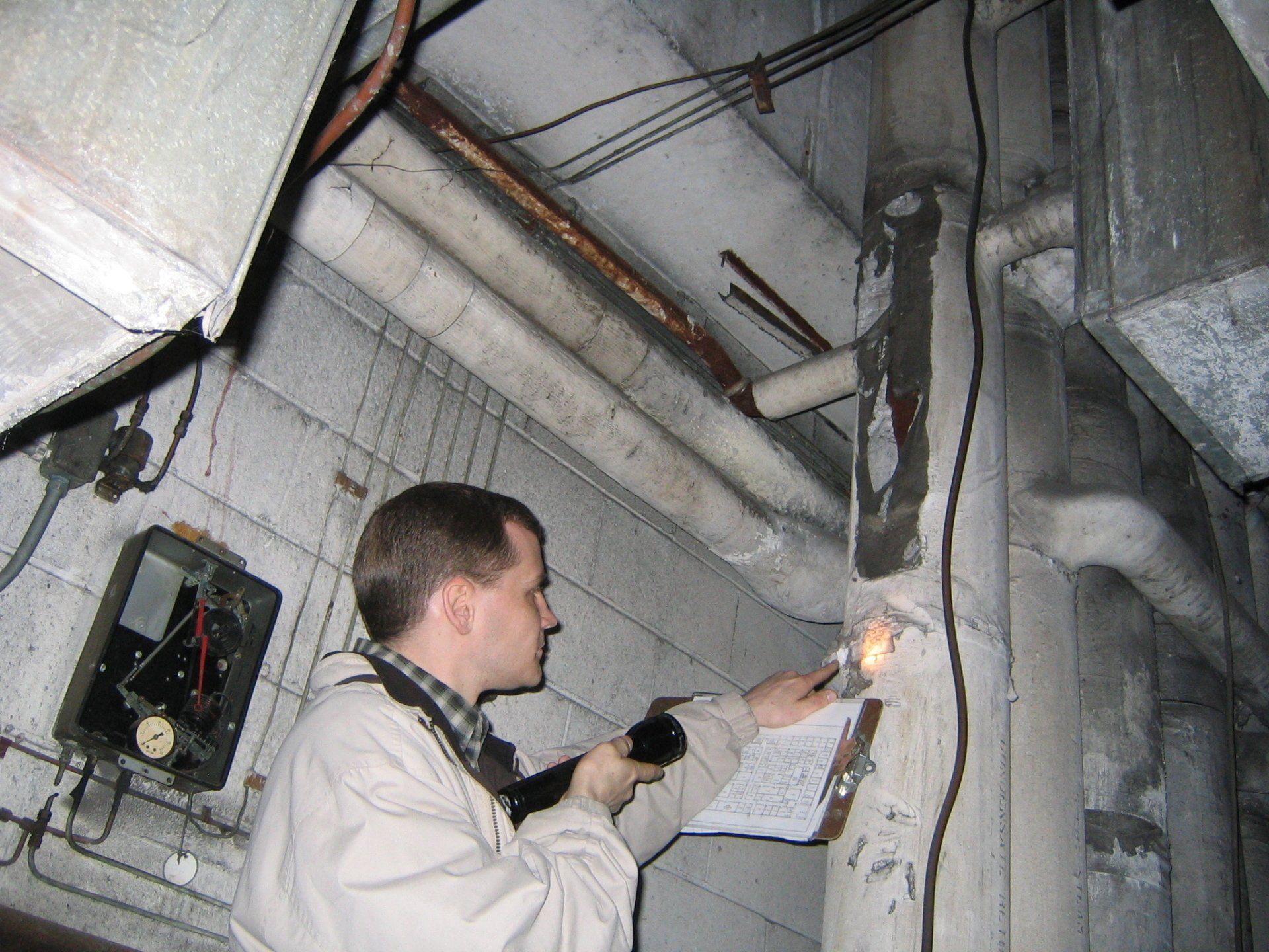 A man is looking at a pipe with a flashlight