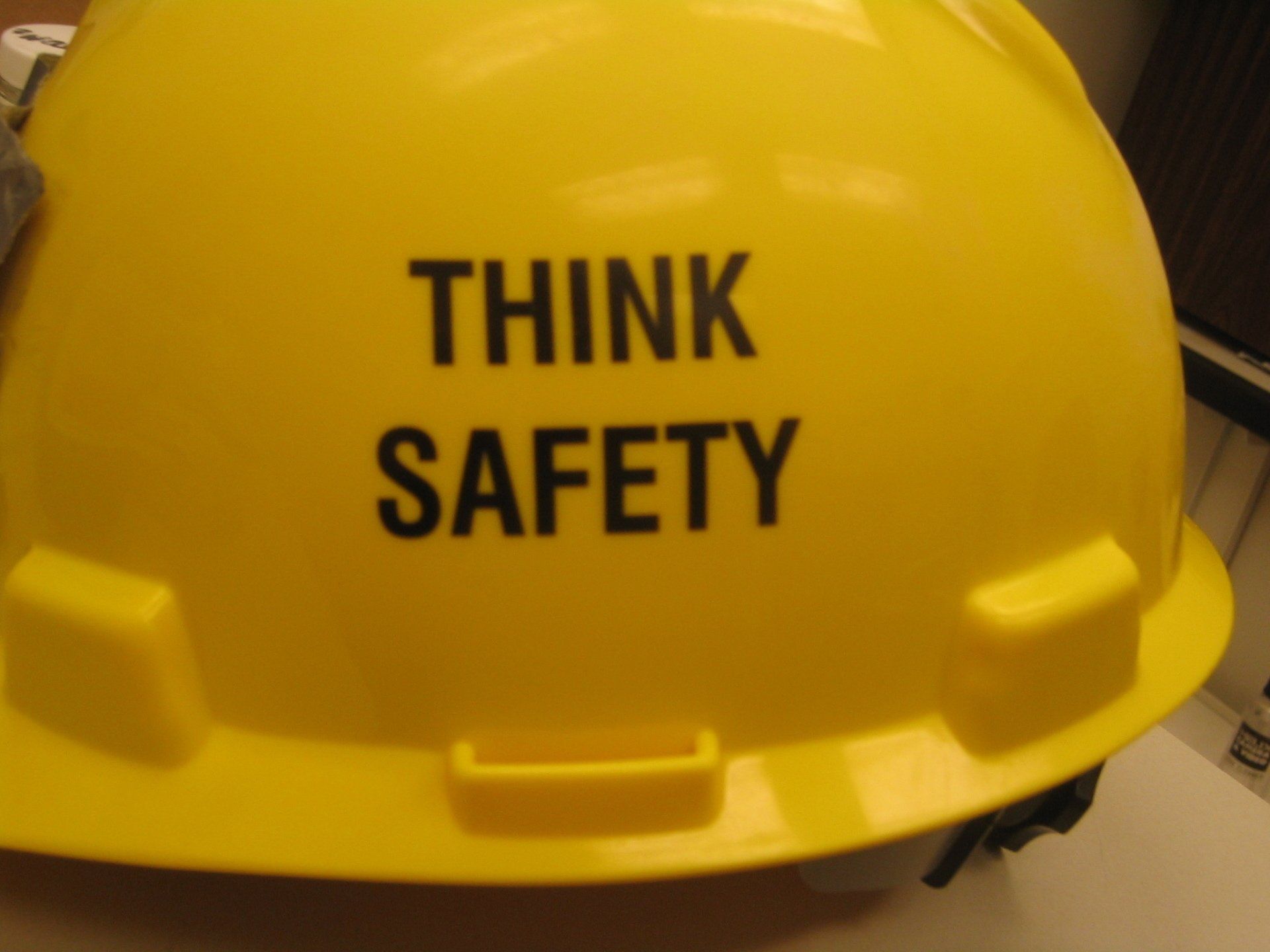 A yellow hard hat that says think safety on it