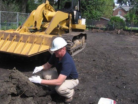 A man is kneeling in the dirt in front of a bulldozer