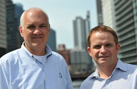 Two men are standing next to each other in front of a city skyline