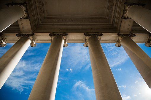 Looking up at the columns of a building with a blue sky in the background.