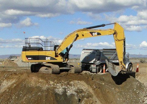 A cat excavator is digging a hole in the dirt