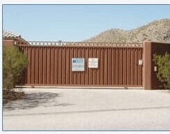 Brown metal security gate in front of a building; mountain backdrop.