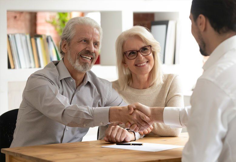 Happy Old Couple Clients Make Financial Deal Handshake — Saint James, MN — Laurels Agency Inc Happy Old Couple Clients Make Financial Deal Handshake — Saint James, MN — Laurels Agency Inc