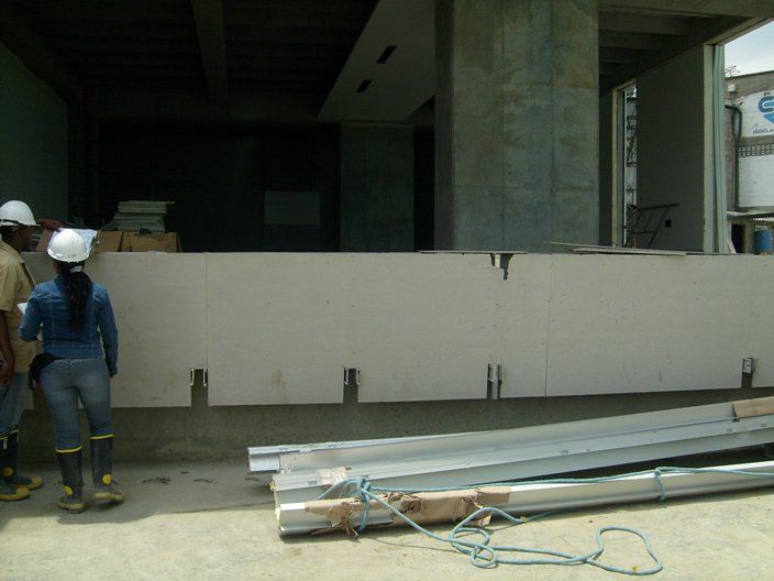 Obreros de la construcción inspeccionando una estructura de hormigón; interior del edificio sin terminar, herramientas y materiales.
