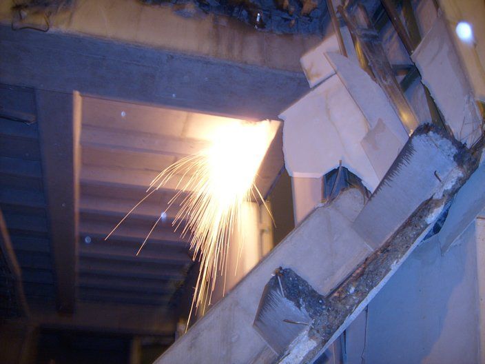 Saltan chispas al cortarse una viga de metal en un entorno industrial.