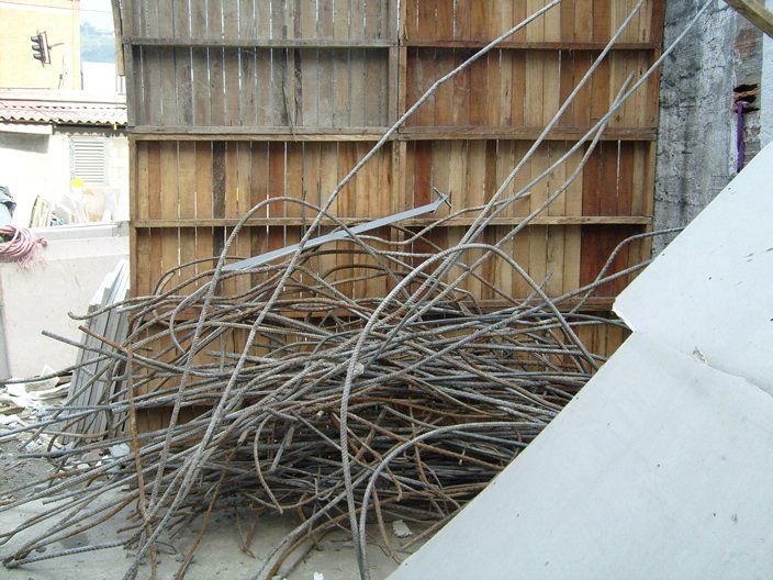 Pila de varillas metálicas dobladas delante de una estructura de madera.