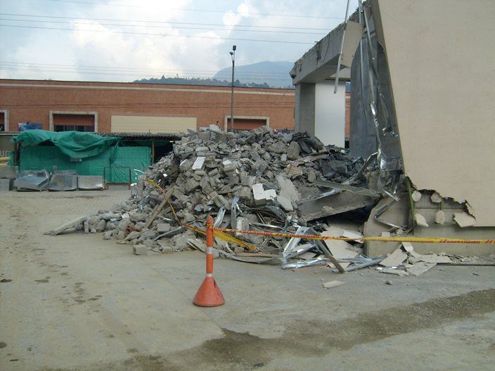 Montón de escombros y desechos frente a un edificio parcialmente demolido.