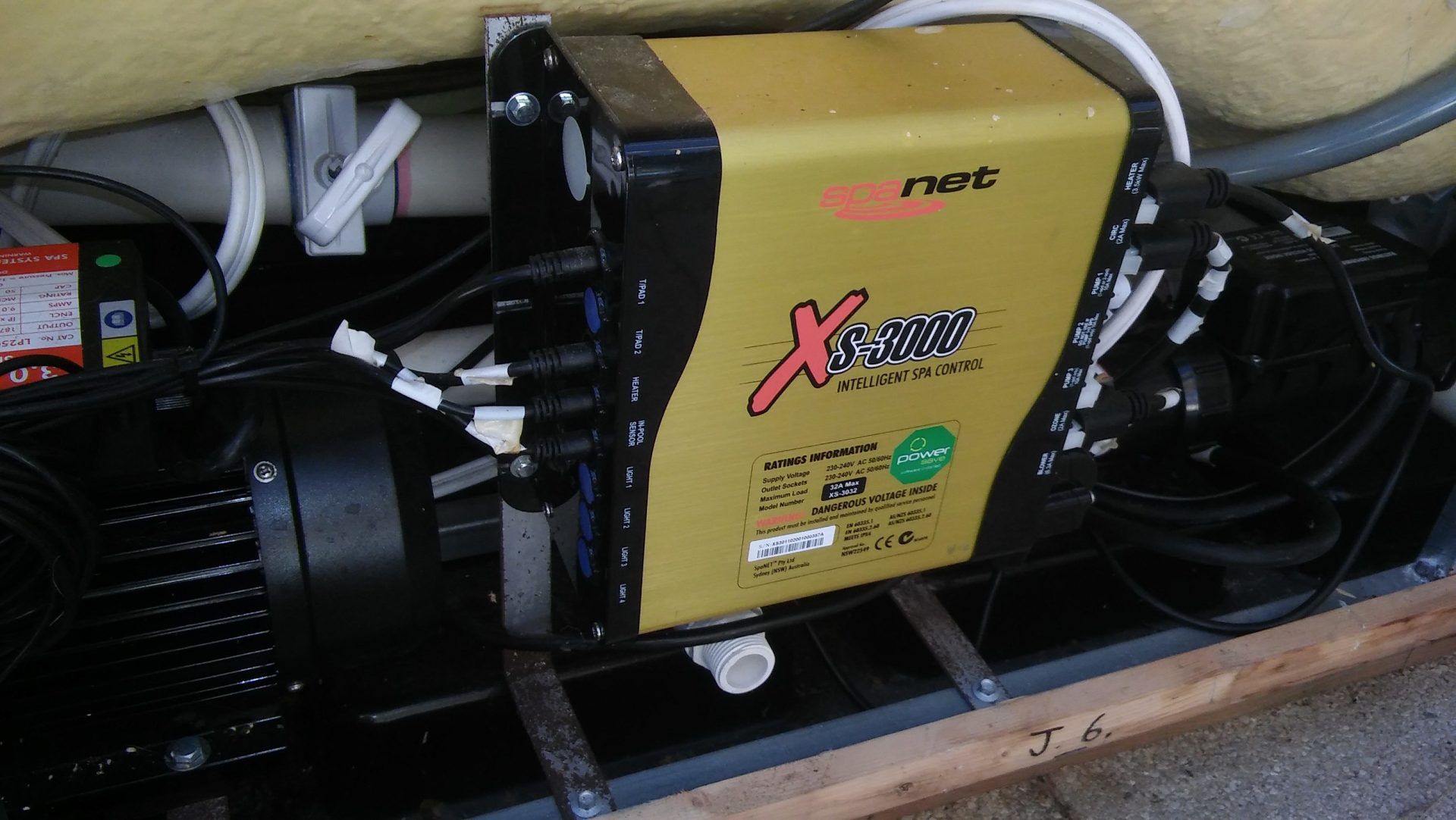 Yellow and black industrial machine with fans and wiring mounted inside a wooden crate