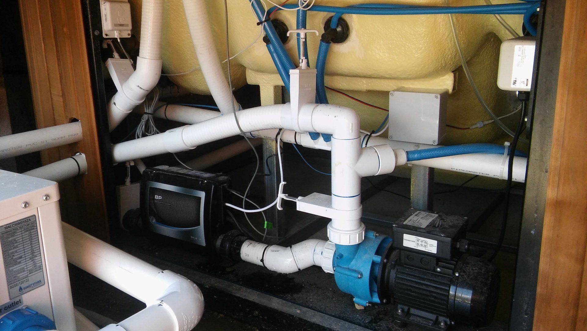 Industrial pump and white PVC pipes in a mechanical equipment compartment