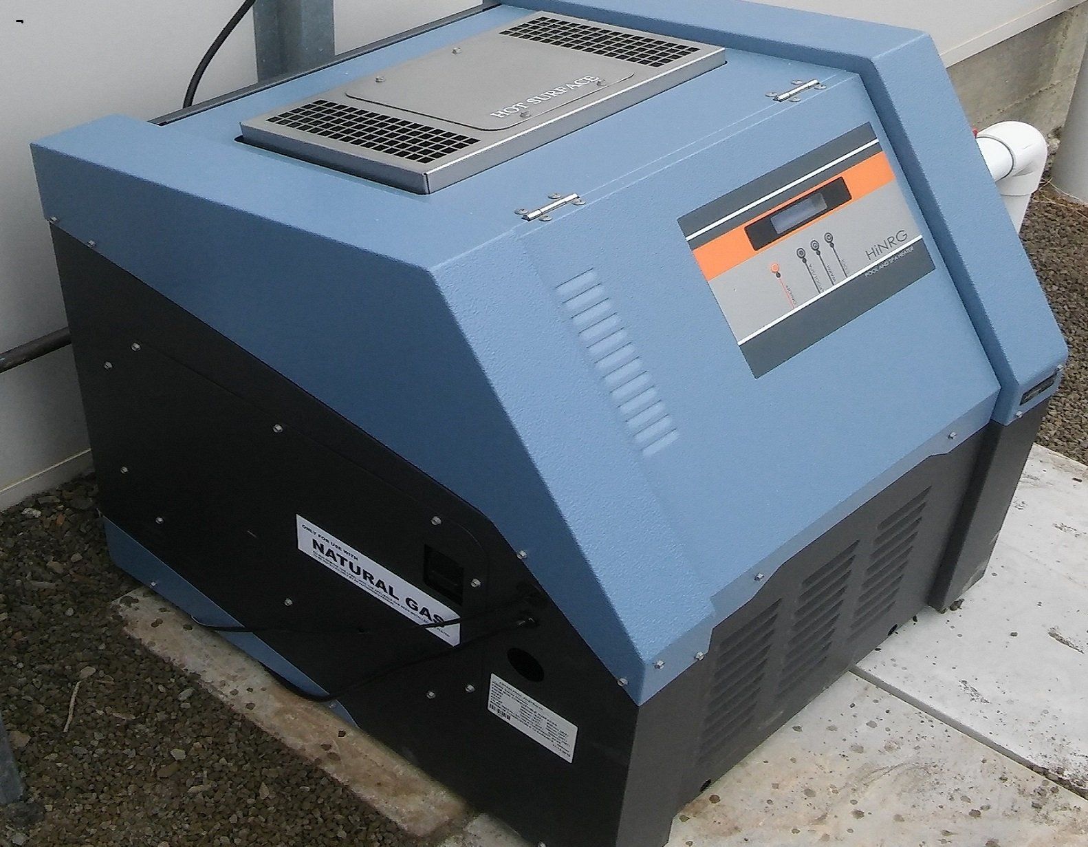Blue industrial machine with vented top and control panel, sitting outdoors on a concrete surface