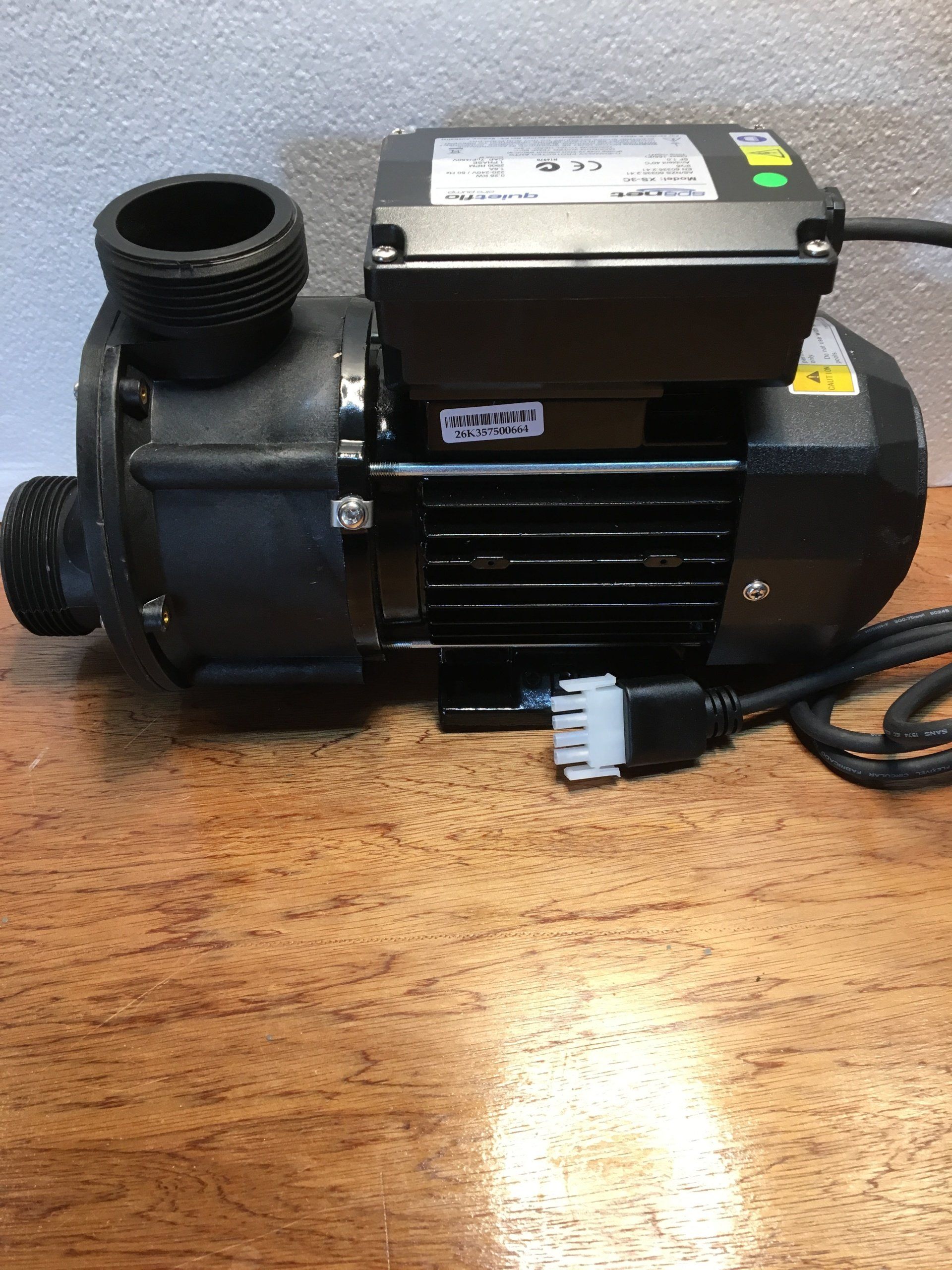 Black electric water pump with attached power cord on a wooden table