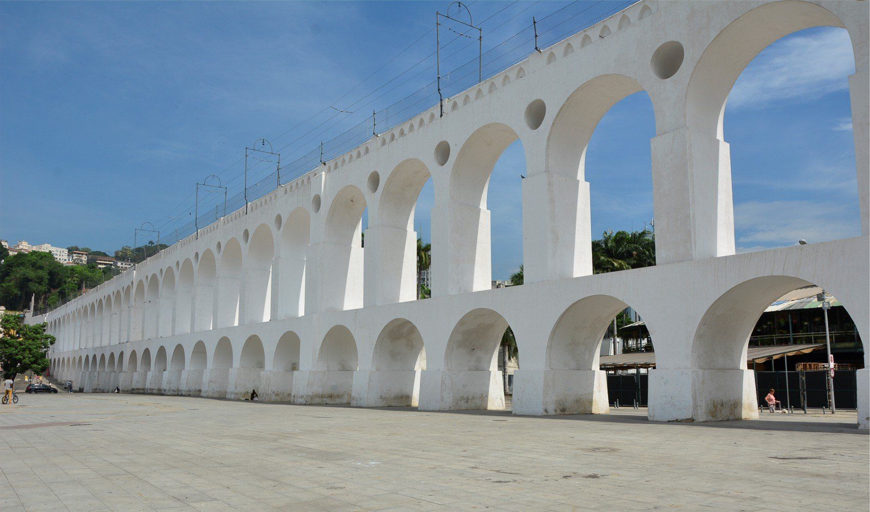 Uma ponte branca com arcos e um céu azul ao fundo