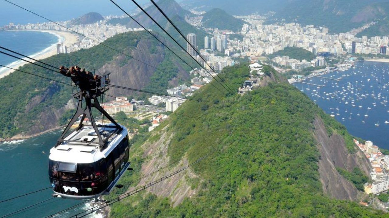 Um teleférico está subindo uma montanha com vista para uma cidade