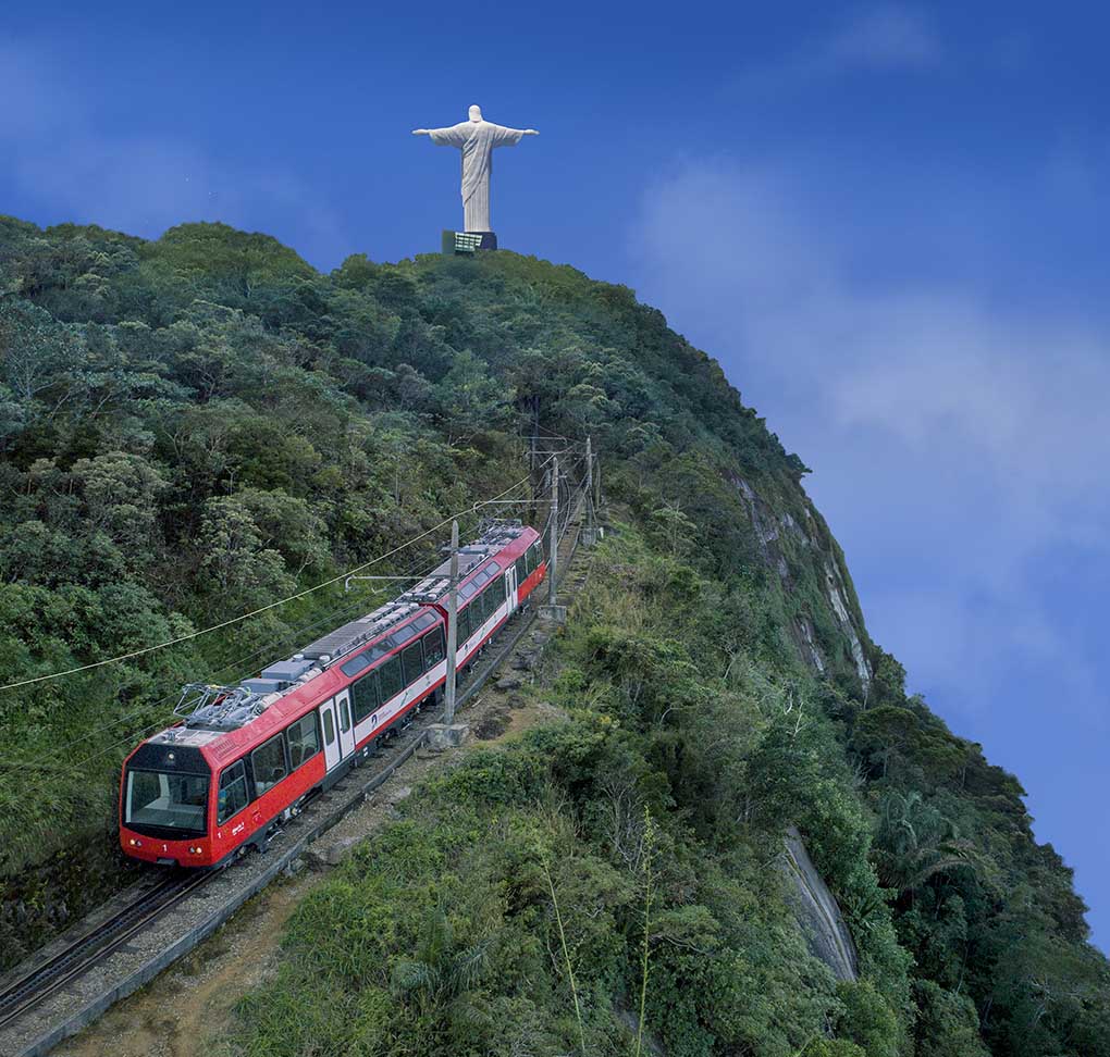 Um trem subindo uma colina com uma estátua de Jesus no topo