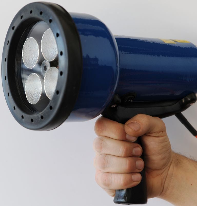 A person is holding a blue flashlight in their hand