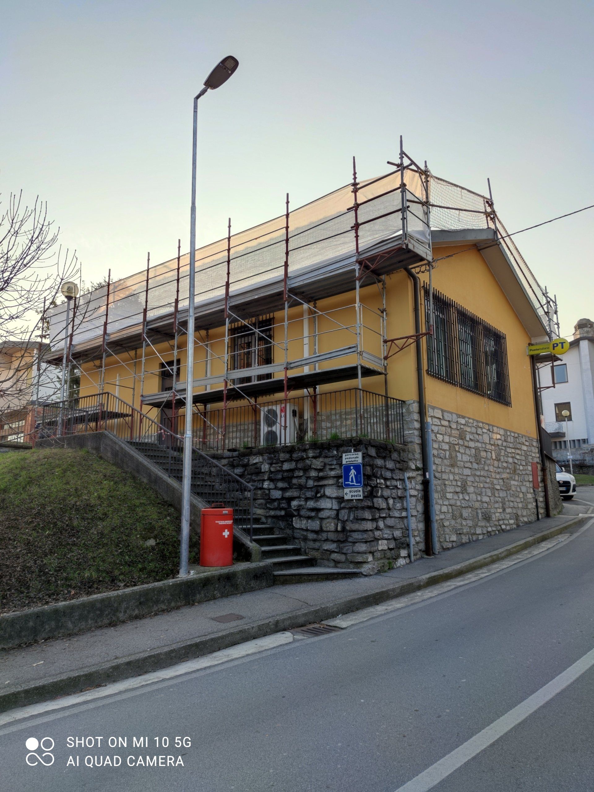 Edificio con impalcature; facciata in stucco giallo e pietra, in fase di ristrutturazione.