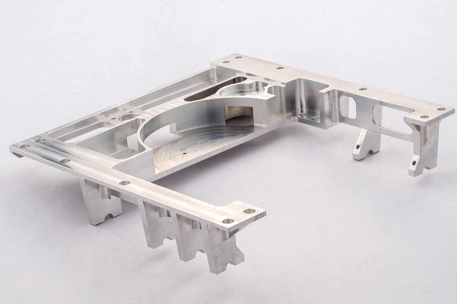 Zilverkleurig metalen onderdeel met een rechthoekig frame, uitsparingen en steunbeugels.