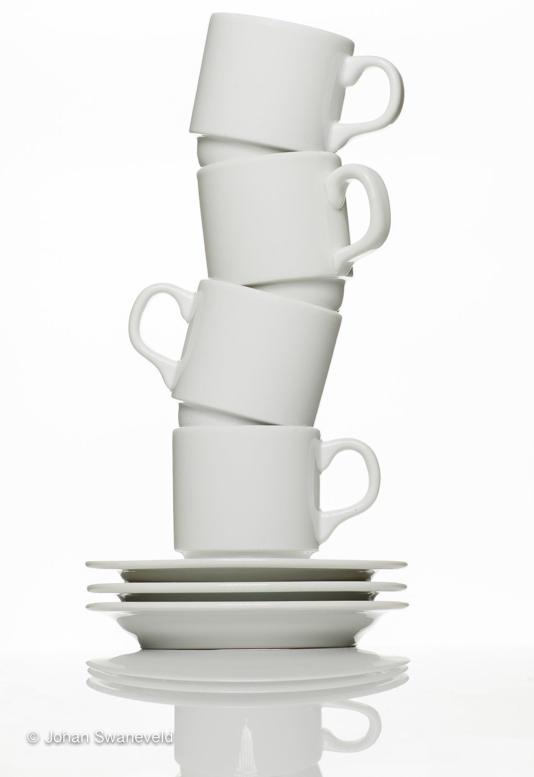 Een stapel van vier witte koffiekopjes, in evenwicht gehouden door twee schoteltjes.
