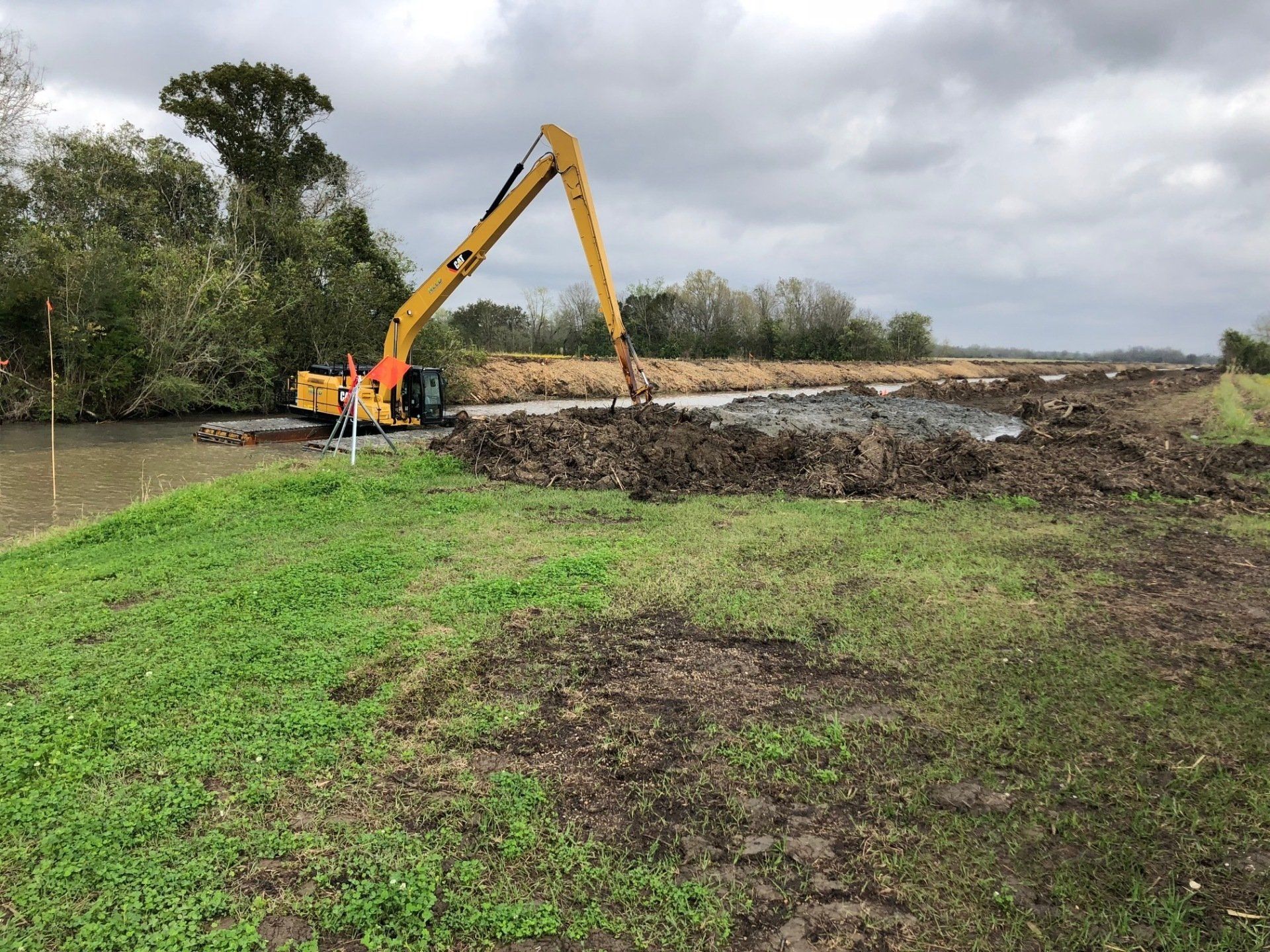 A large yellow excavator is digging a hole in a field.