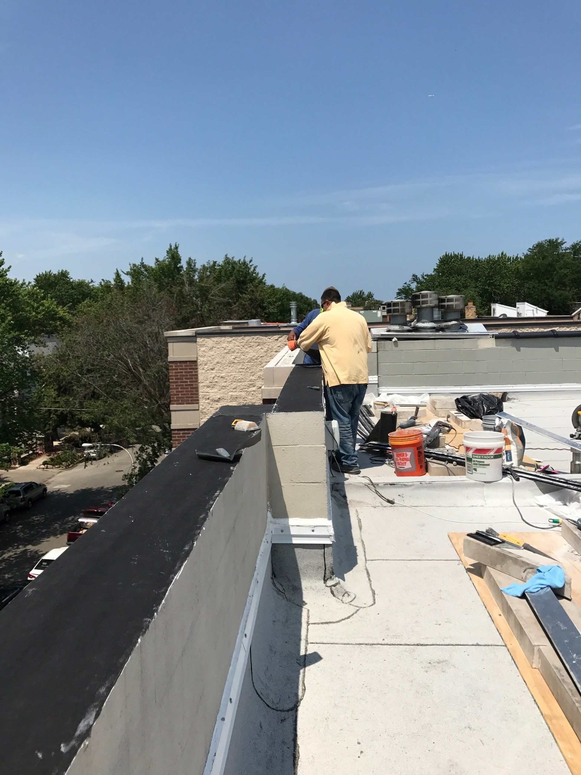 WickRight parapet vent and vapor permeable membrane being installed on wet brick-block parapet wall with renaissance stone