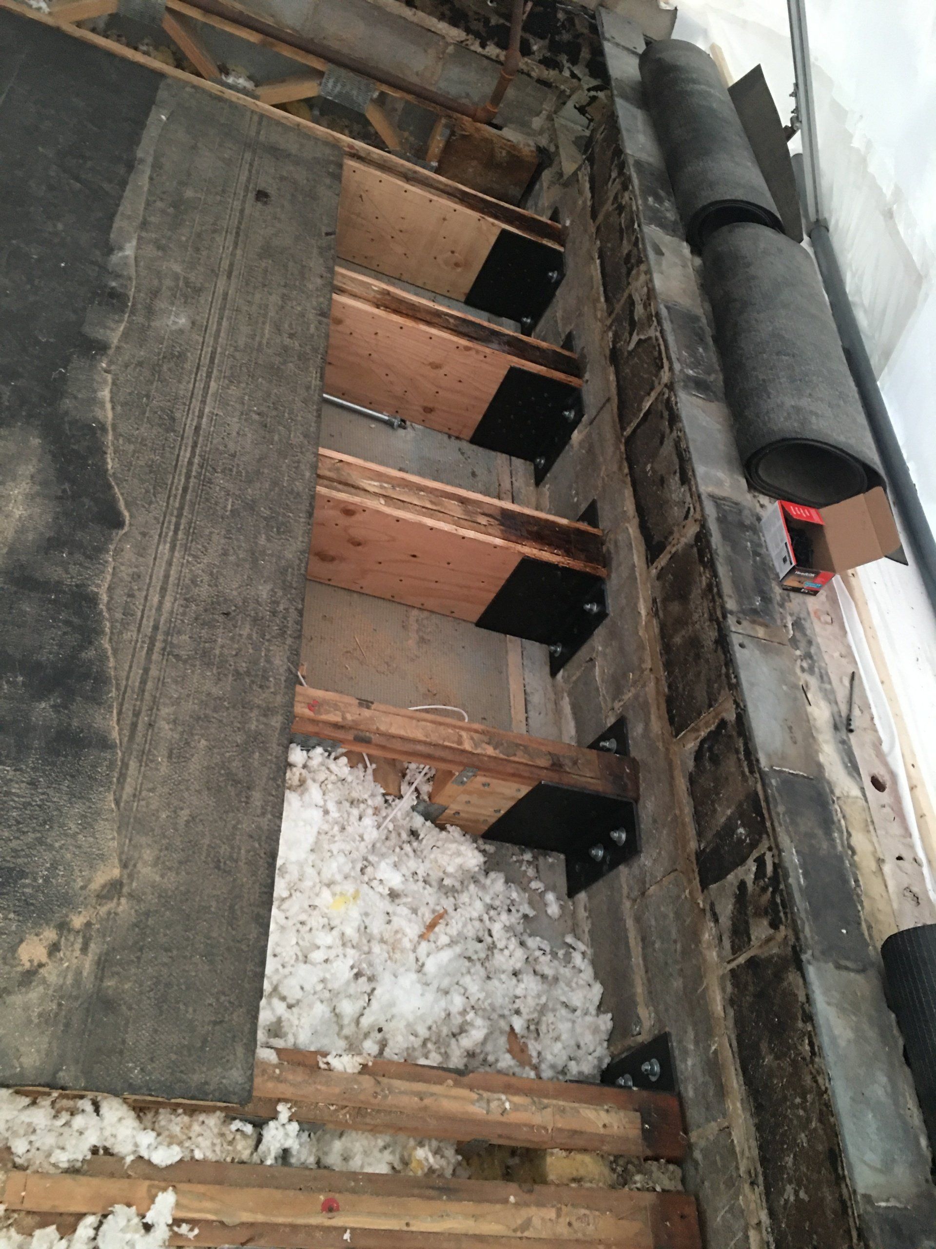 WickRight truss repair brackets installed on water damaged trusses embedded in split face block walls under 365 Tent