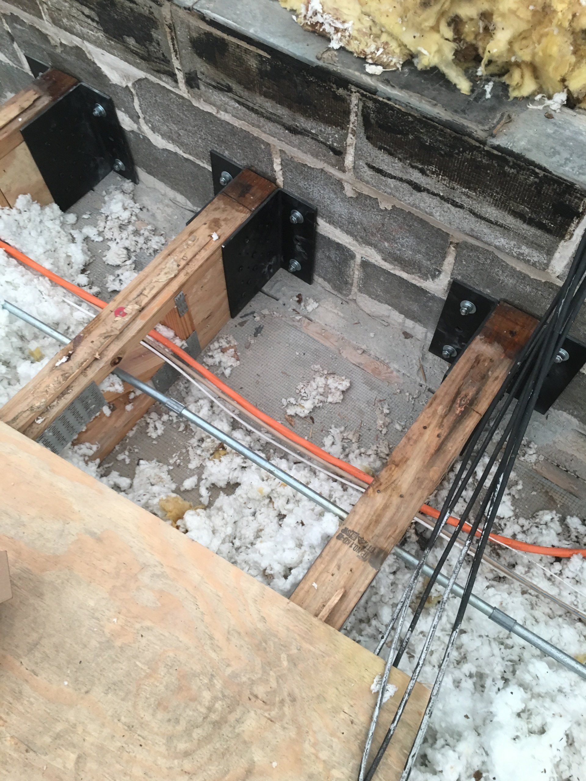 WickRight truss bracket repair system installed on water damaged roof trusses embedded in wet split face block wall, Chicago