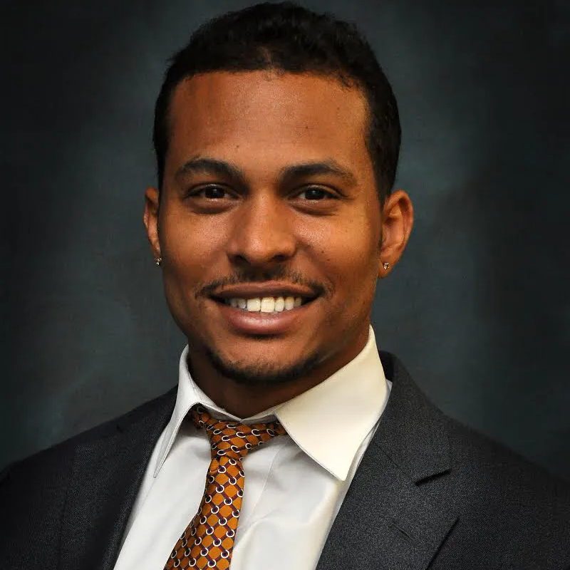 A man in a suit and tie smiles for the camera