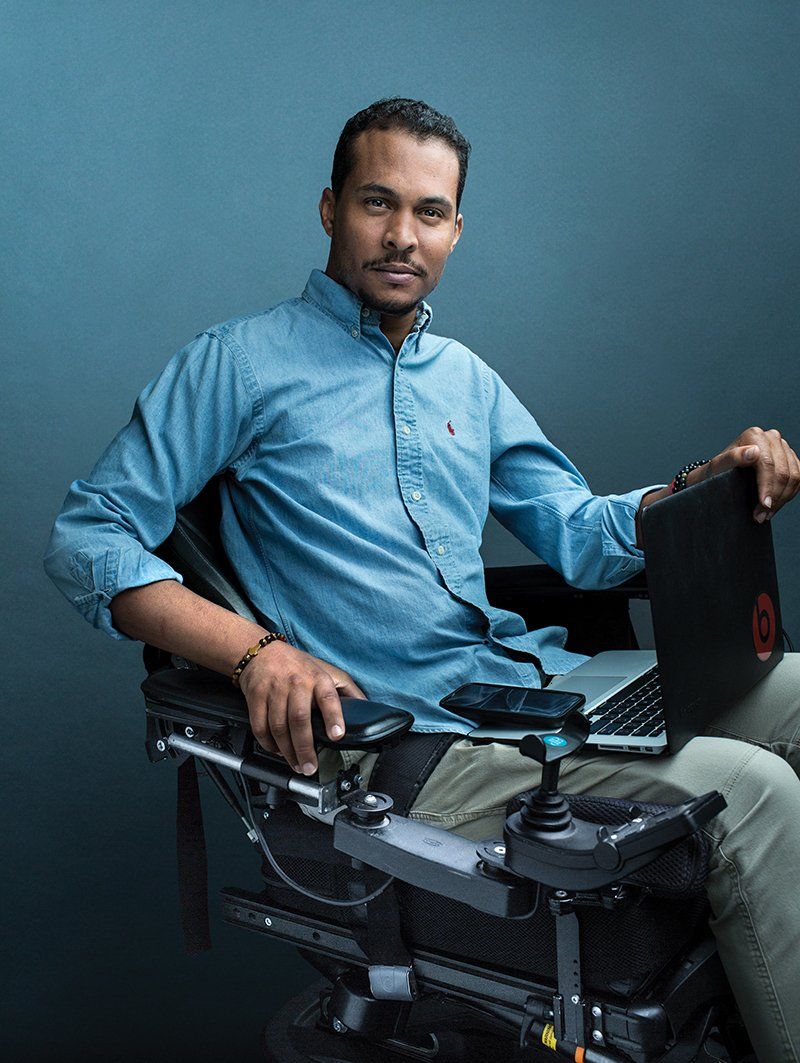 A man in a wheelchair is sitting in front of a laptop computer.