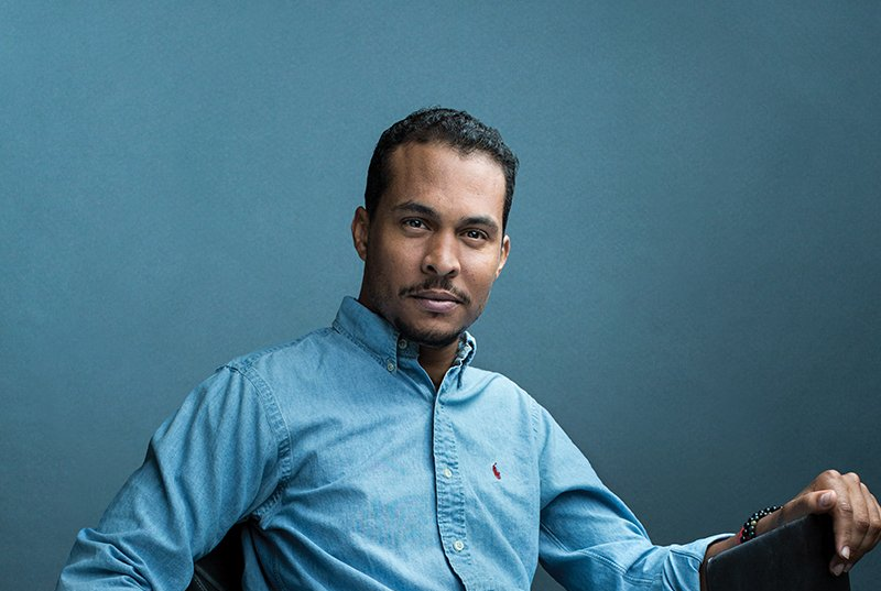 A man in a blue shirt is sitting in a chair.