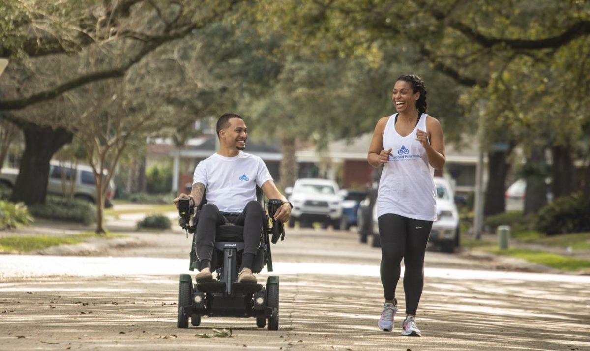 A man in a wheelchair and a woman are walking down a sidewalk.